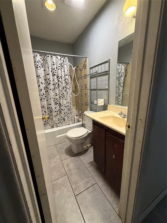 Bathroom featuring large-format tile flooring, a vanity with a solid-surface countertop and integrated sink, a built-in tub with shower surround, and a wall-mounted mirror