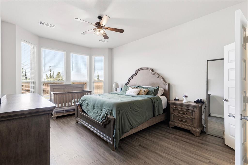Bedroom featuring wood-finish flooring, a multi-paneled door, and a ceiling fan with integrated lighting