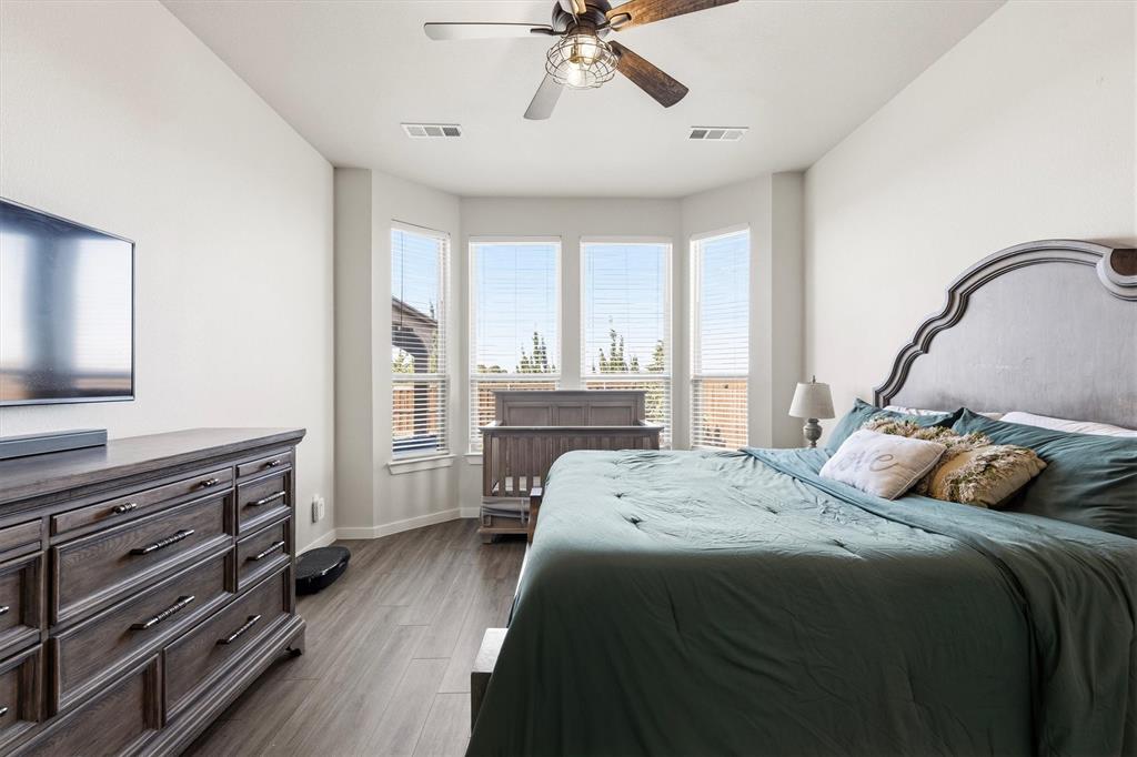 Bedroom featuring wood-finish flooring, a vaulted ceiling with a multi-blade ceiling fan, and a large bay window assembly