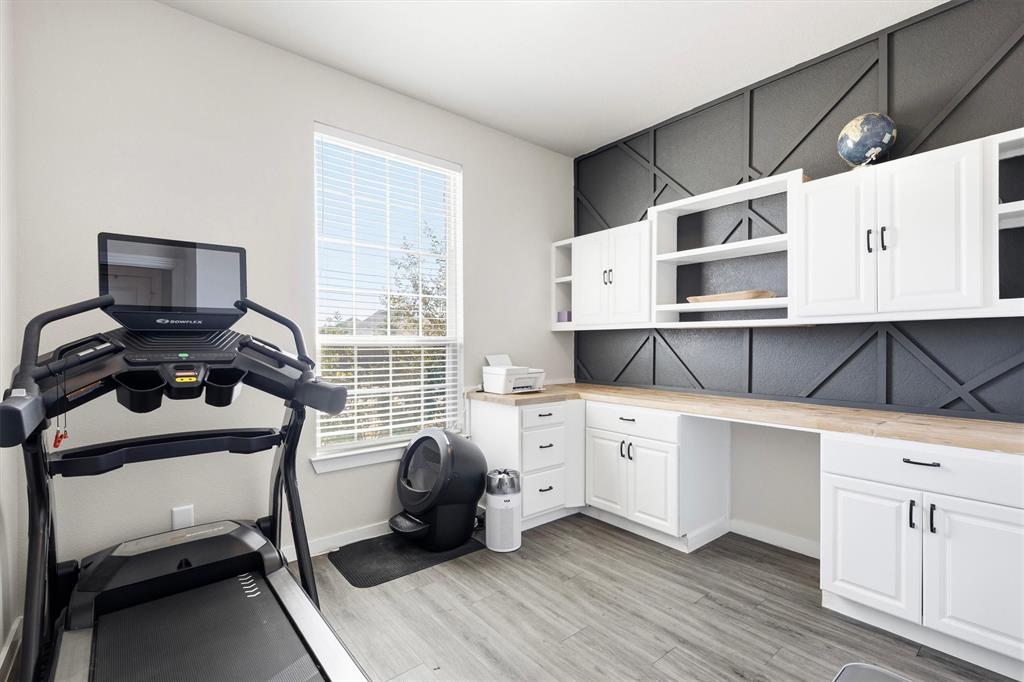 Custom built-in cabinetry featuring white shaker-style doors, matte black hardware, and light wood-tone countertops set against a charcoal-toned geometric wall accent