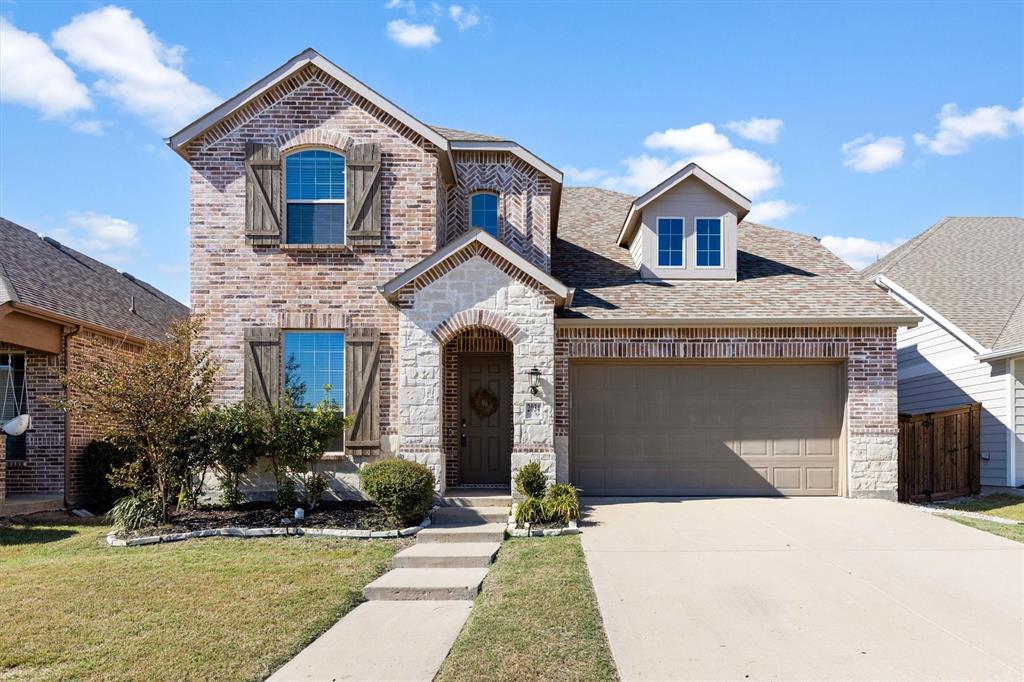 Two-story exterior featuring multi-toned brick veneer, stone masonry detailing, decorative wood-style shutters, arched window accents, and a dual-car garage Two-story exterior featuring multi-toned brick veneer, stone masonry detailing, decorative wood-style shutters, arched window accents, and a dual-car garage