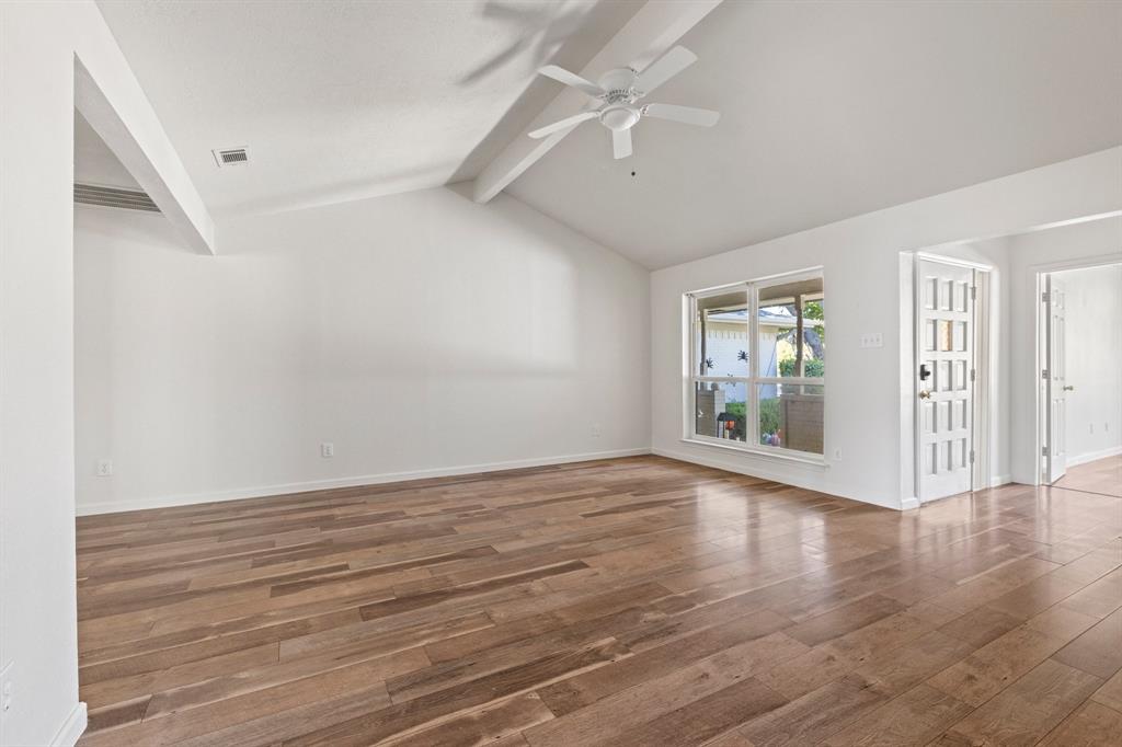 Vaulted ceiling with an integrated white ceiling fan, wood-finish flooring, and a multi-lite exterior entry door
