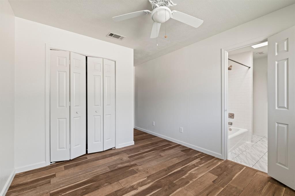 Interior room featuring wood-finish flooring, white paneled bi-fold closet doors, and a ceiling-mounted fan with integrated light