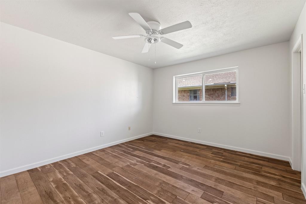Interior space featuring wood-finish flooring, white walls, and a ceiling fan with integrated lighting