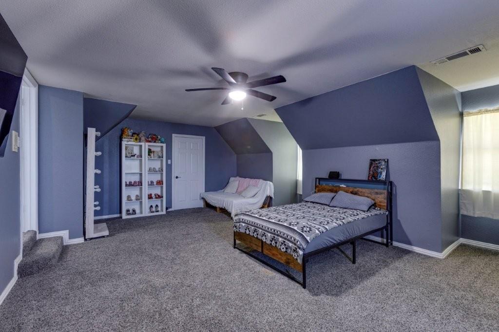 Spacious room featuring vaulted ceilings, neutral carpeting, and a ceiling fan with integrated lighting