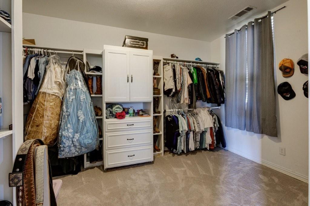 Custom walk-in closet featuring white built-in cabinetry, tiered shelving units, integrated dresser drawers, and dual-level hanging rods