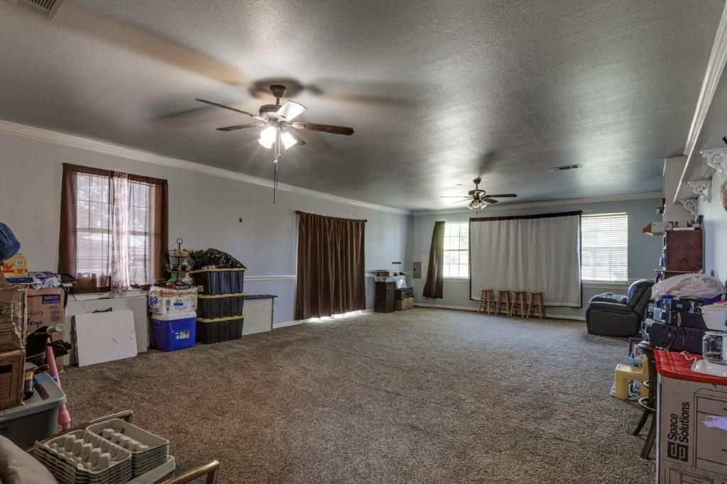 Expansive room featuring carpeted flooring, dual ceiling fans, crown molding, chair rail trim, and multi-pane windows