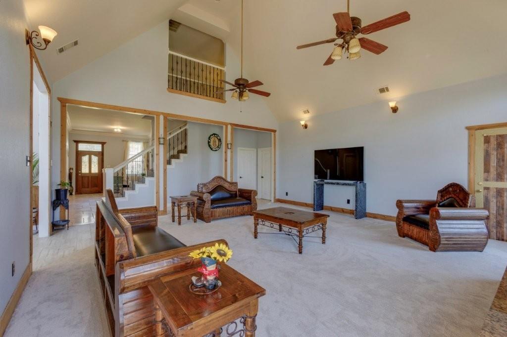 Vaulted ceiling featuring dual ceiling fans, recessed wall sconces, wood-trimmed entryways, and an elevated interior overlook with decorative railing