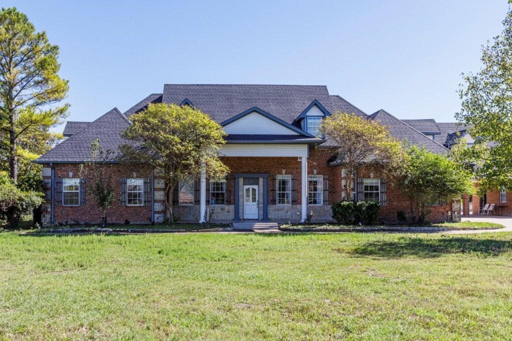 Traditional brick exterior featuring a covered front porch, multi-gabled roofline, decorative window shutters, and dormer accents