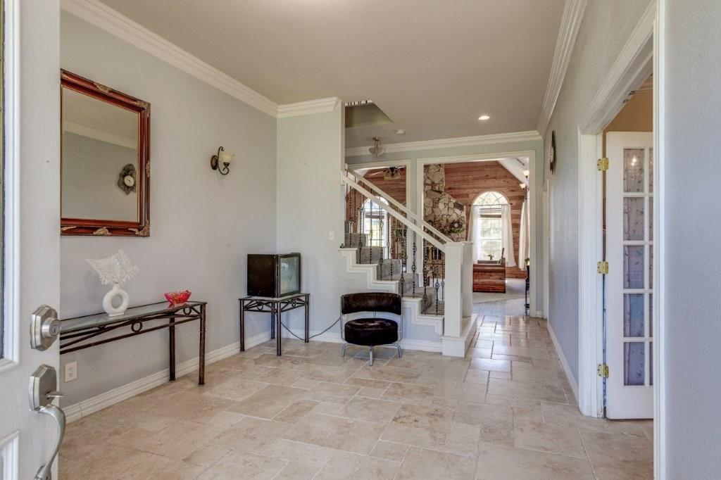 Foyer featuring tile flooring, crown molding, and a staircase with an iron balustrade