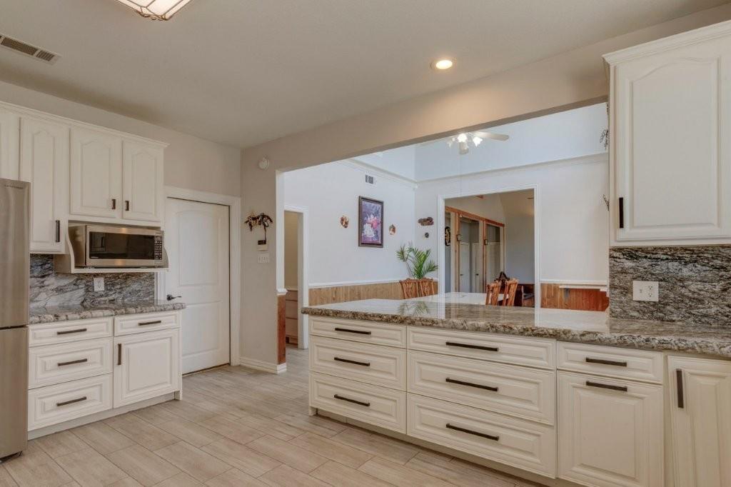 Kitchen featuring white cabinetry, stone-finish countertops, matte black hardware, built-in microwave, and wood-finish tile flooring