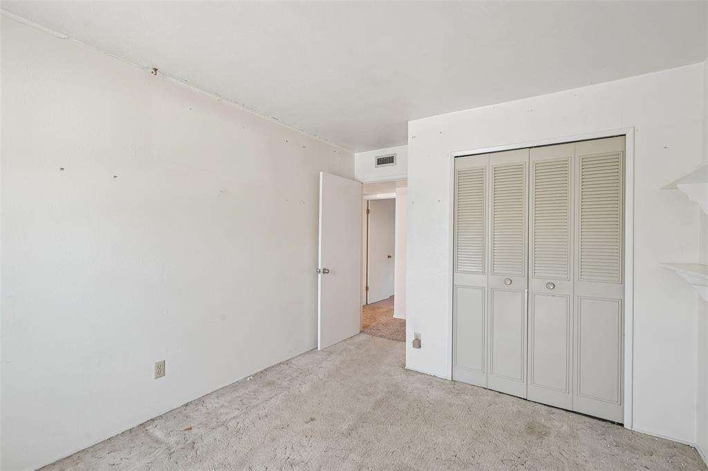 A bedroom with a full louvered closet.