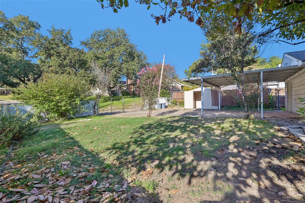Mature trees and open lawn across the corner-lot backyard.