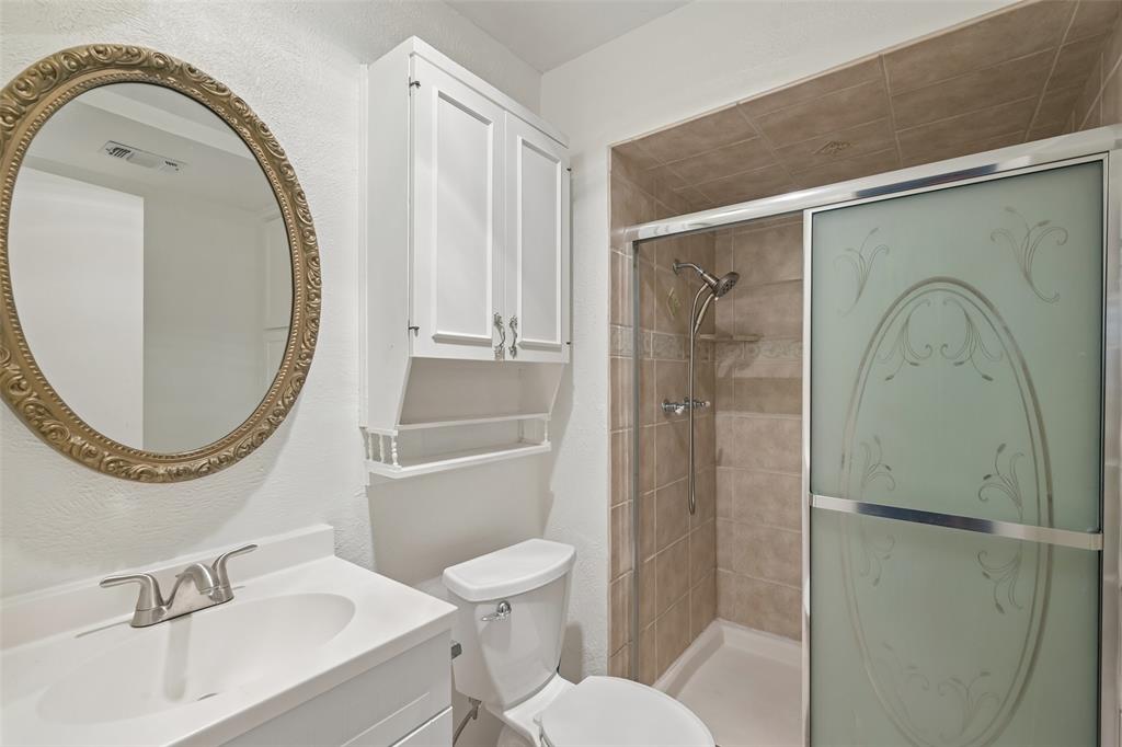 A walk-in shower with a glass door and a single vanity.
