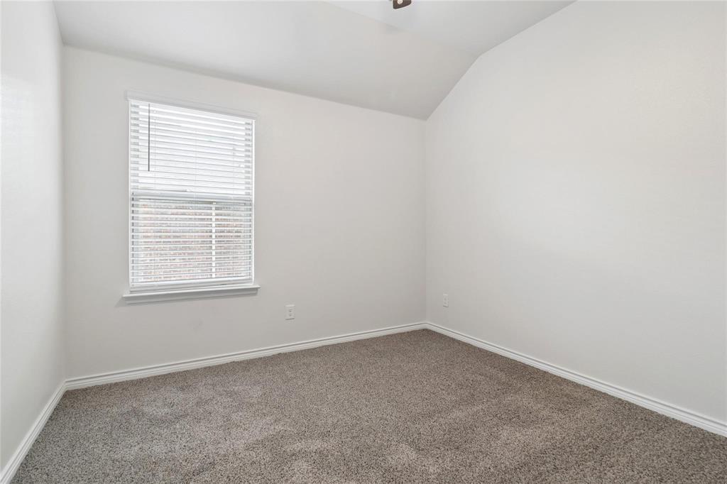 Neutral-toned room featuring a vaulted ceiling, wall-to-wall carpeting, and a window with horizontal blinds
