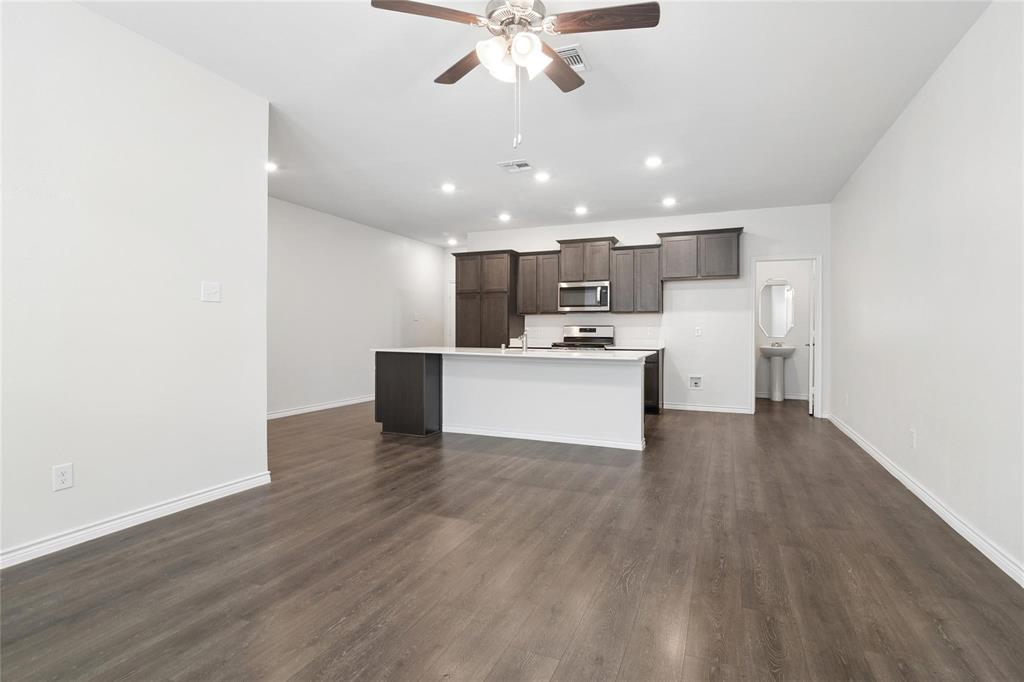 Kitchen featuring dark wood cabinetry, a central island with a white countertop, recessed ceiling lighting, and wood-finish flooring