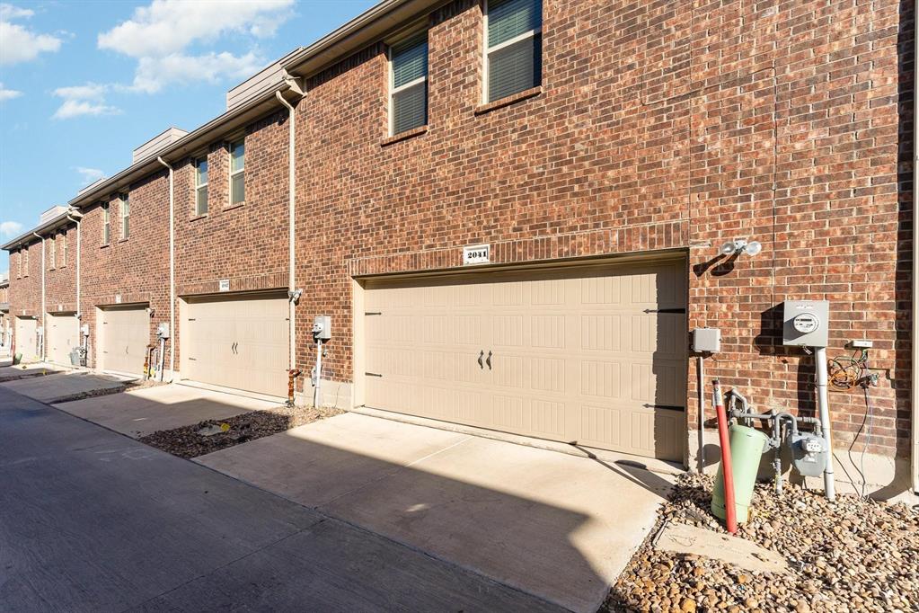 Multi-story brick exterior featuring attached dual-car garages, concrete driveways, and upper-level windows