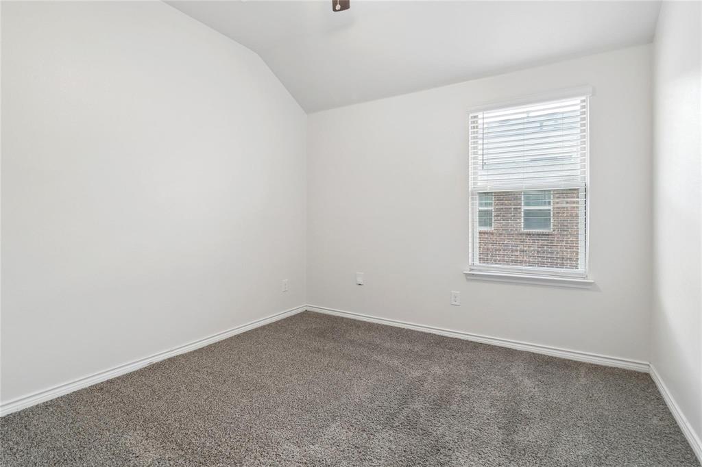 Neutral-toned carpeted flooring, vaulted ceiling, and single window with installed horizontal blinds