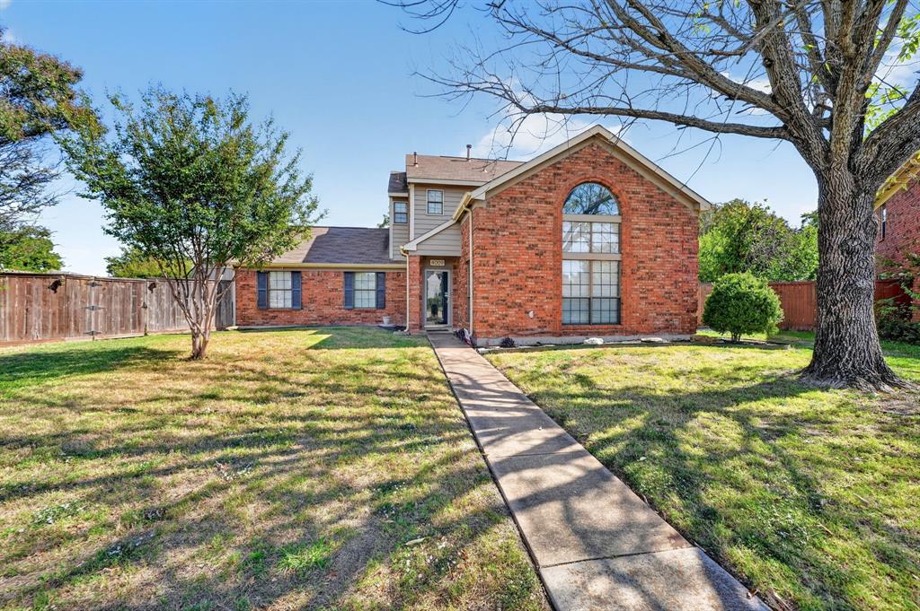 Multi-story brick exterior featuring a prominent arched window, shingle roofing, and a concrete walkway Multi-story brick exterior featuring a prominent arched window, shingle roofing, and a concrete walkway