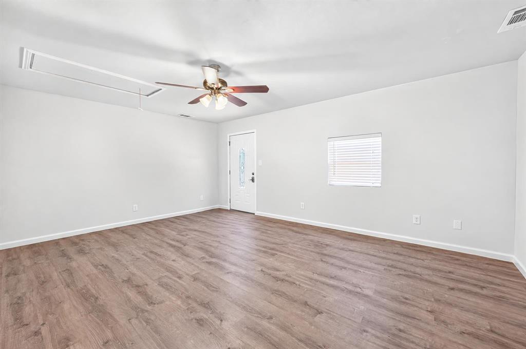 Interior space featuring wood-finish flooring, a ceiling fan with integrated lighting, and a single-panel exterior door with a decorative glass insert