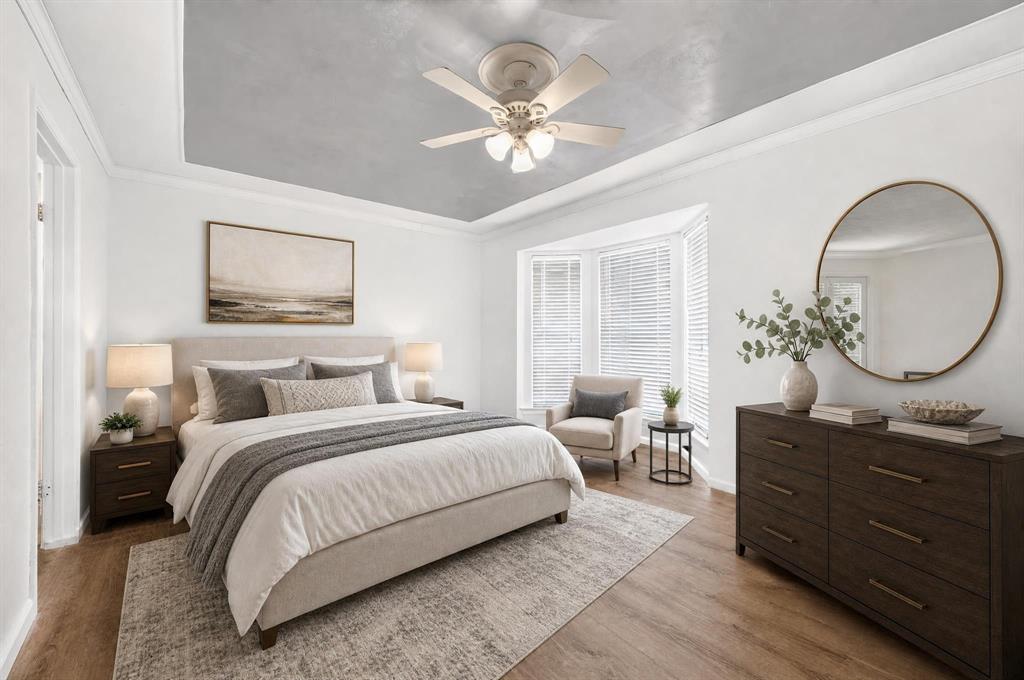 Tray ceiling with grey finish, wood-finish flooring, and bay window featuring integrated blinds