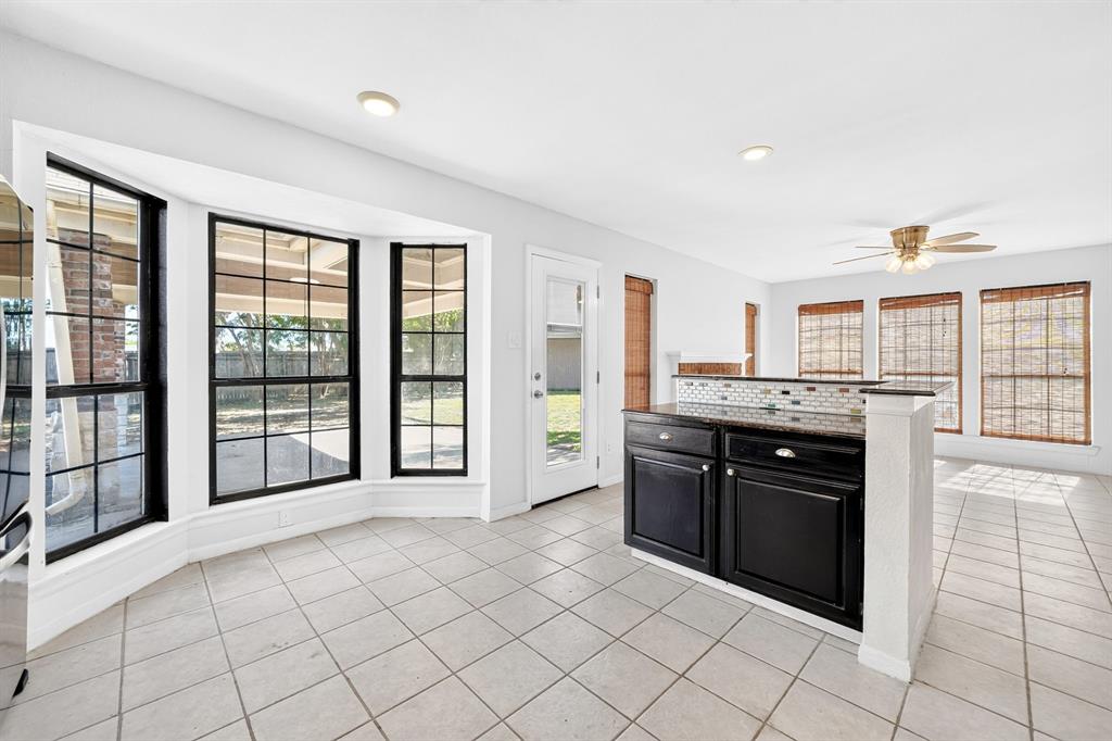 Bay window featuring large-pane grid windows, tile flooring, breakfast bar with dark cabinetry, stone-finish countertop, and recessed ceiling lighting