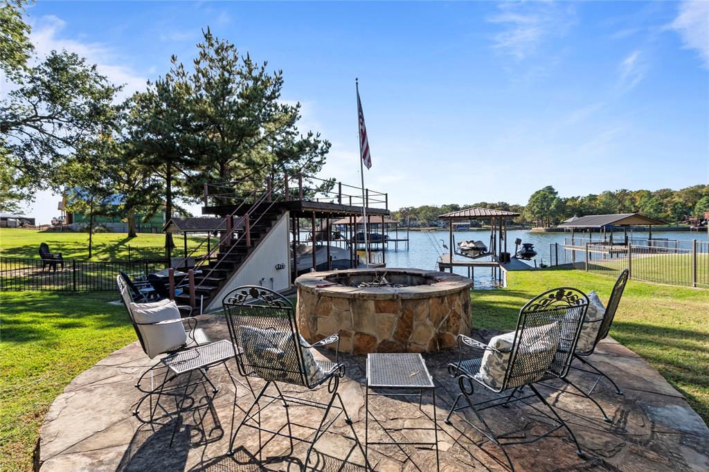 Flagstone patio featuring a circular stone fire pit, metal-railed waterfront staircase, and private boat slip