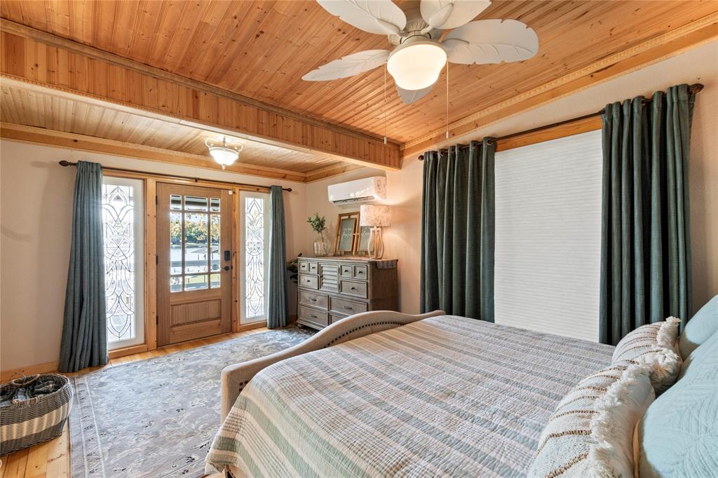 Wood-paneled ceiling, ceiling fan with integrated lighting, glass-paneled entry door with sidelights, and wall-mounted ductless climate control unit