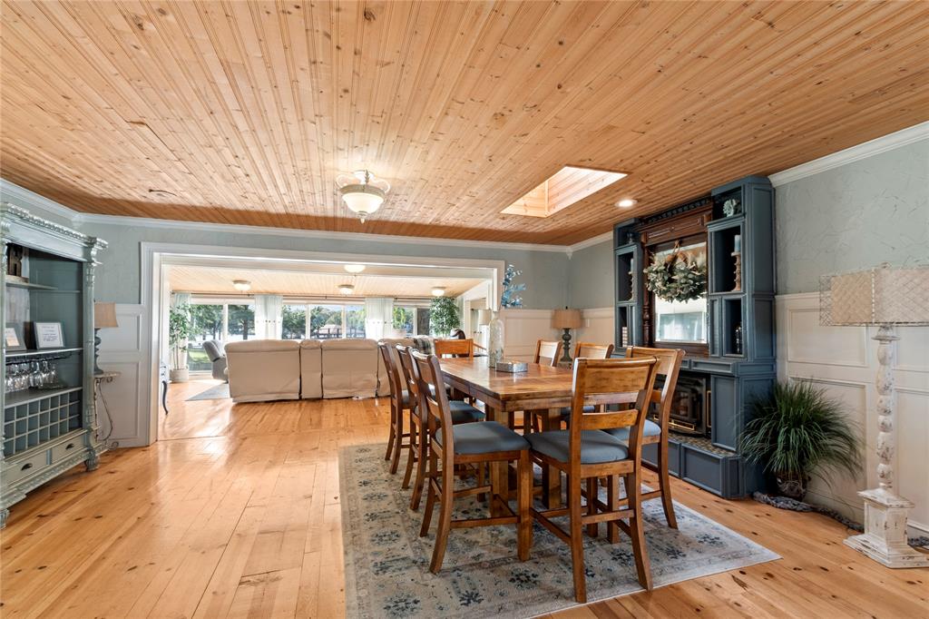 Natural wood-plank ceiling, skylight, light-toned wood-finish flooring, built-in cabinetry with integrated shelving, and white wainscoting Natural wood-plank ceiling, skylight, light-toned wood-finish flooring, built-in cabinetry with integrated shelving, and white wainscoting
