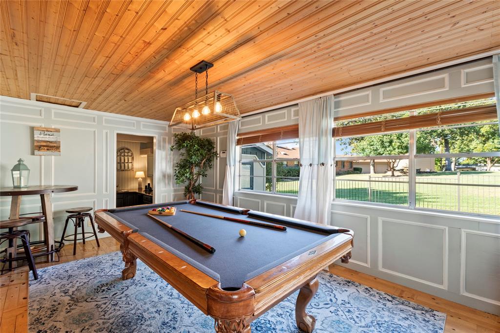 Beadboard wood-plank ceiling, wall wainscoting with decorative molding, large multi-pane windows, and a box-frame metal light fixture Beadboard wood-plank ceiling, wall wainscoting with decorative molding, large multi-pane windows, and a box-frame metal light fixture