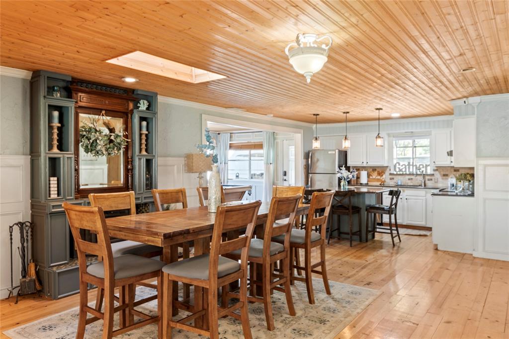 Tongue-and-groove wood ceiling featuring a built-in skylight, wood-finish flooring, custom floor-to-ceiling built-in cabinetry, and white wainscoting Tongue-and-groove wood ceiling featuring a built-in skylight, wood-finish flooring, custom floor-to-ceiling built-in cabinetry, and white wainscoting