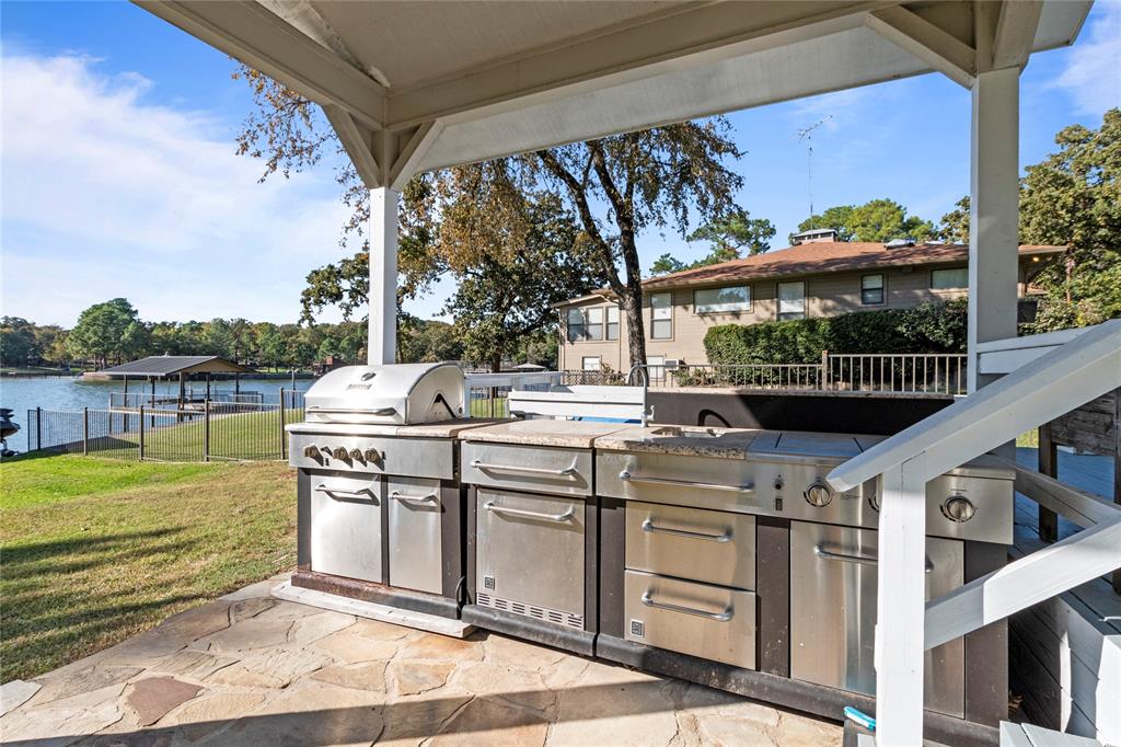 Covered patio featuring an outdoor kitchen with stainless steel grill, stone-surfaced countertop, integrated sink, and flagstone flooring