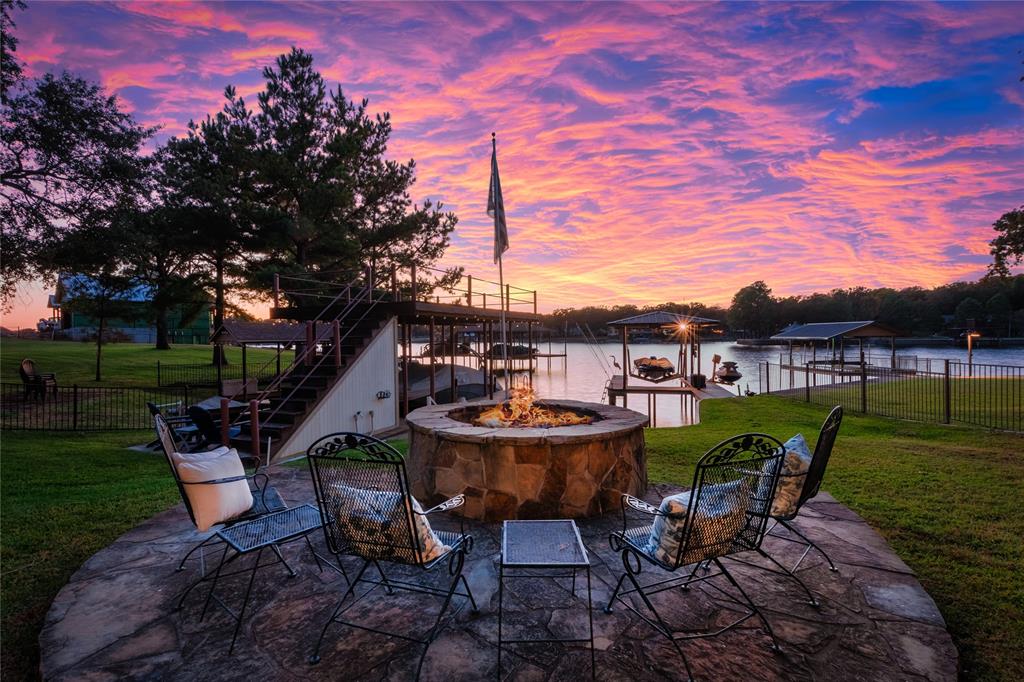 Flagstone patio featuring a circular stone fire pit, metal perimeter fencing, and a multi-level dock structure Flagstone patio featuring a circular stone fire pit, metal perimeter fencing, and a multi-level dock structure