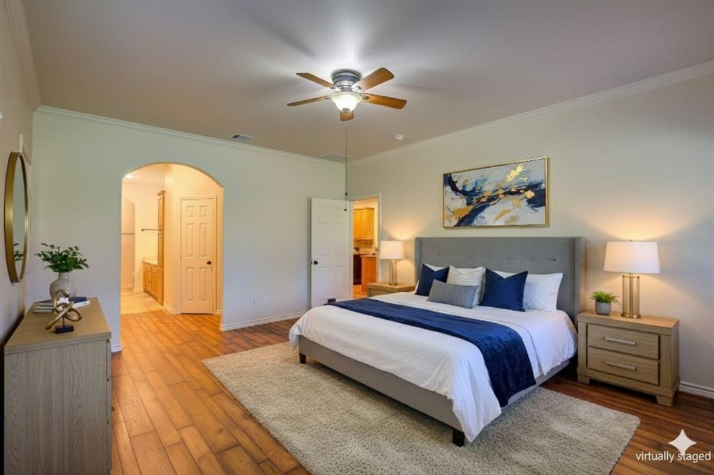 Virtually Staged Primary Bedroom with ornamental molding, hardwood / wood-style flooring, arched walkways, and ceiling fan
