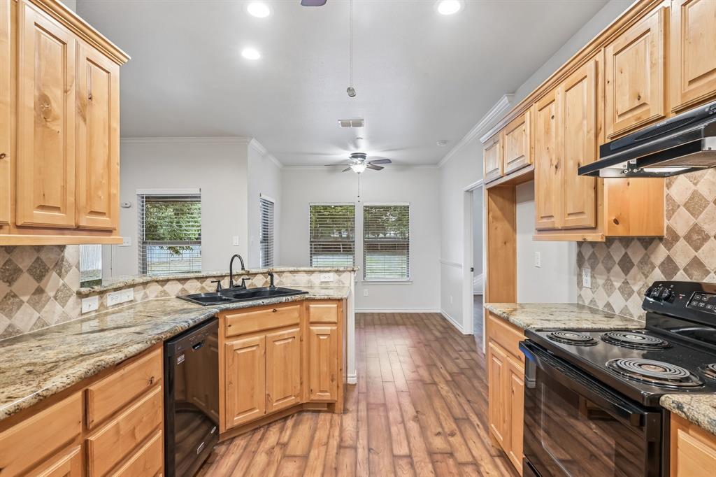 Kitchen featuring wood cabinetry, granite countertops, tile backsplash, and wood-finish flooring