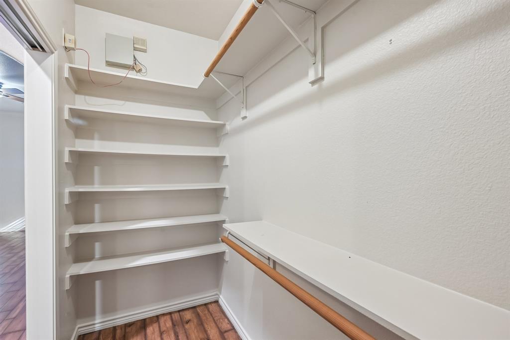 Built-in shelving, hanging rods, wood-finish flooring, and white painted walls