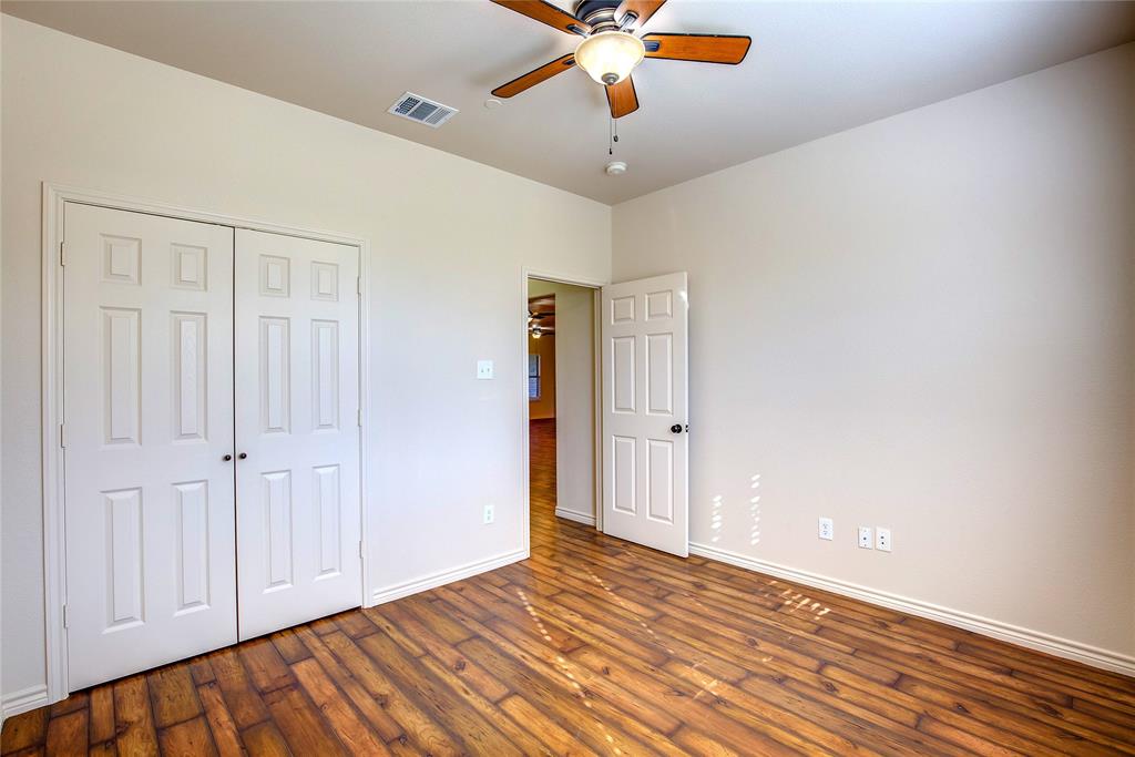 Secondary bedroom with ceiling fan, dark wood finished floors, and a closet
