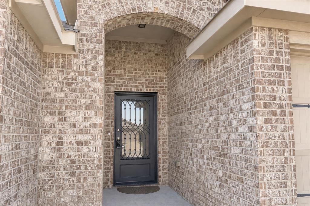 Full-brick exterior featuring an arched entryway, stone-finish masonry, and a black metal-framed glass front door with decorative scrollwork Full-brick exterior featuring an arched entryway, stone-finish masonry, and a black metal-framed glass front door with decorative scrollwork