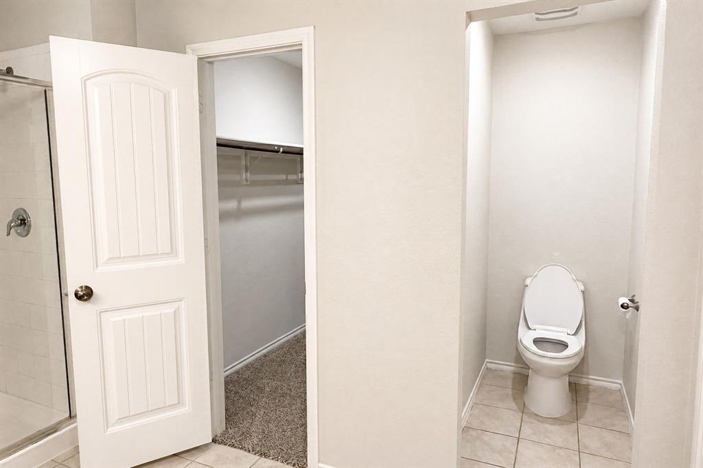 Walk-in closet featuring wire shelving and textile flooring, paired with a dedicated water closet and a glass-enclosed shower featuring a metallic fixture