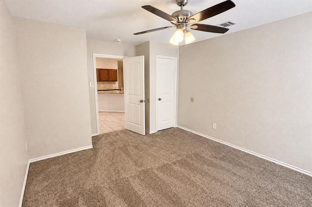 Neutral-toned carpeting, ceiling fan with integrated light fixture, and paneled doors