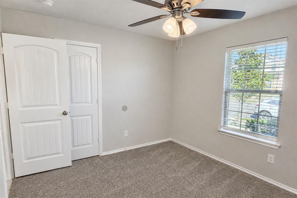 Neutral-toned room featuring neutral carpeting, a ceiling fan with integrated lighting, a single-hung window with horizontal blinds, and a paneled interior door Neutral-toned room featuring neutral carpeting, a ceiling fan with integrated lighting, a single-hung window with horizontal blinds, and a paneled interior door