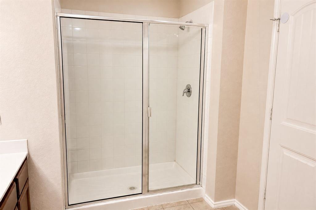 Shower enclosure with chrome-framed glass sliding doors, white tiled walls, and a single-handle faucet