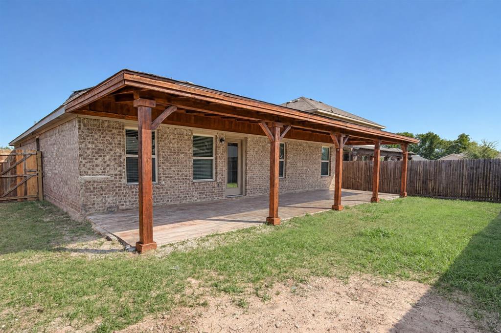 Rear exterior featuring a brick facade, expansive covered patio with wood-post supports, and wood-finish ceiling detailing