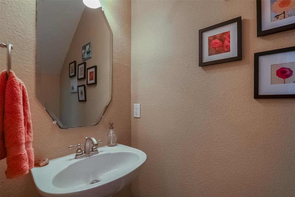 Wall-mounted oval mirror, pedestal sink with dual-handle faucet, and integrated towel hardware