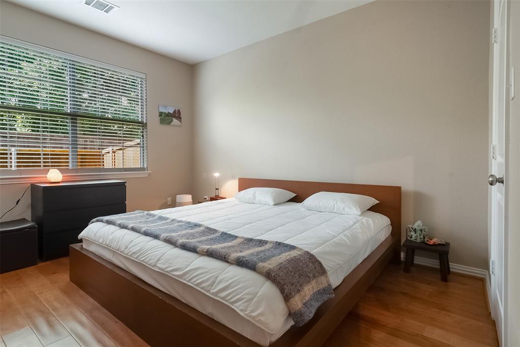 Room featuring wood-finish flooring, neutral wall paint, and a large window with horizontal blinds