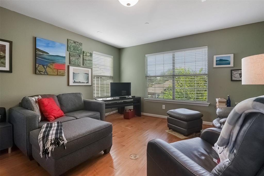 Living area featuring wood-finish flooring, two large windows with horizontal blinds, and a central ceiling light fixture