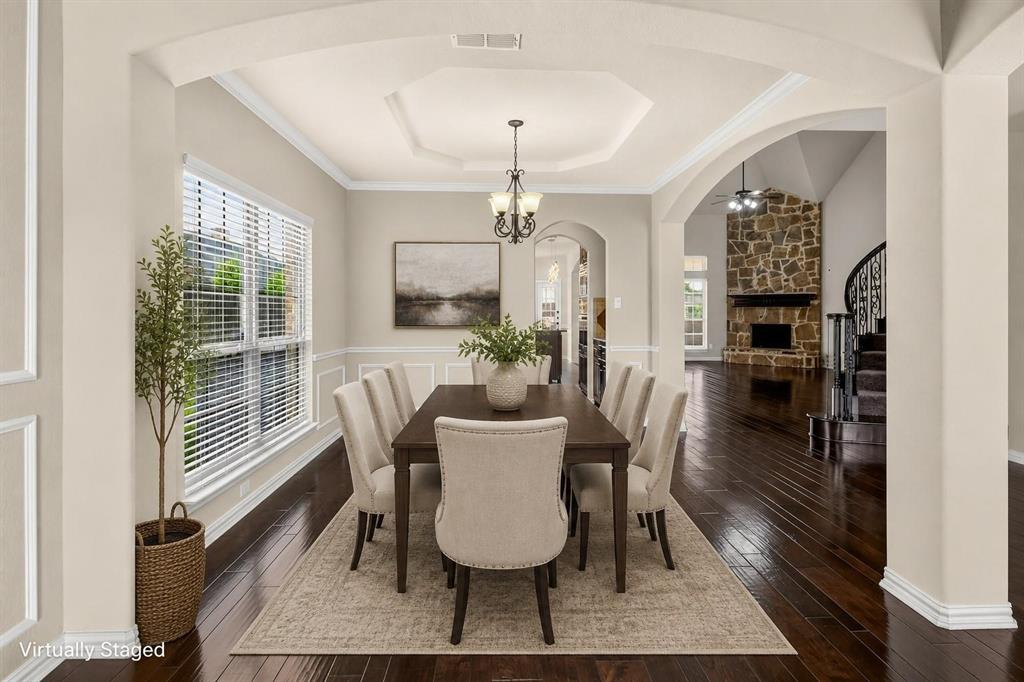 Dining area featuring an octagonal tray ceiling, wainscoting, dark wood-finish flooring, and a multi-light chandelier