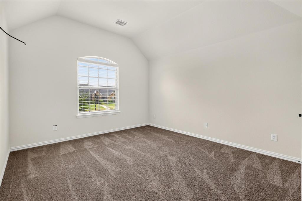 Vaulted ceiling room featuring neutral carpeting and an arched window