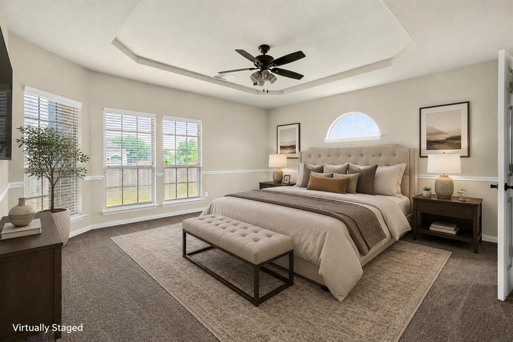 Tray ceiling with central ceiling fan, multiple windows with grid detailing, and arched accent window