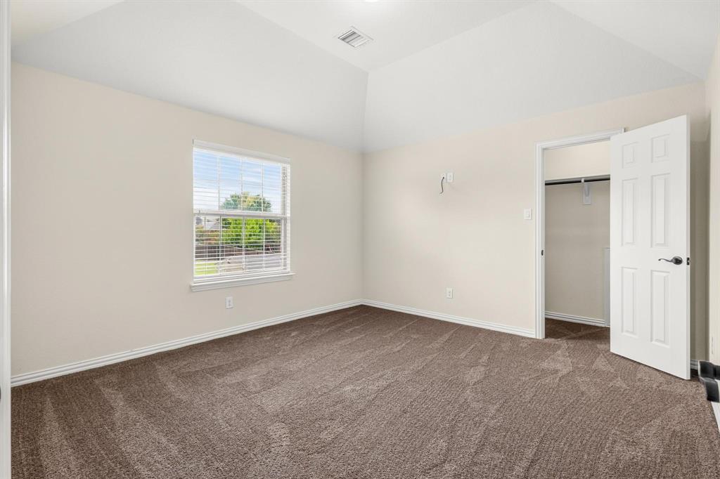 Vaulted ceiling room featuring neutral wall tones, wall-to-wall carpeting, a single-hung window with integrated blinds, and an interior door opening to a closet